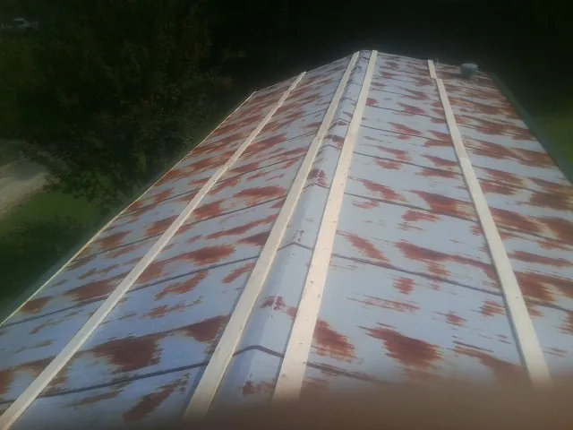 Rusted metal roof panels with new wood purlins before replacement — Storm Damage Roof Repair in Matthews by Roofing Brothers