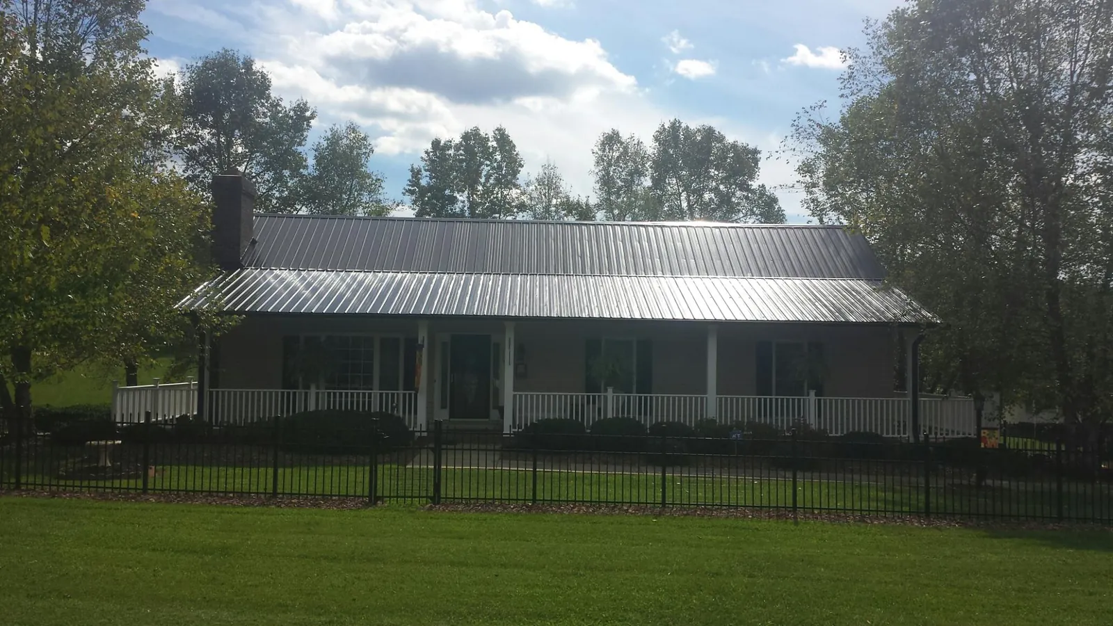 Gray metal roof on a brick ranch with a full width front porch — Gutter Guard Installation work by our crew in Matthews